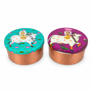 Decorative metal storage jars featuring traditional Pichwai cow and lotus printed lids with crystal-style knobs.
